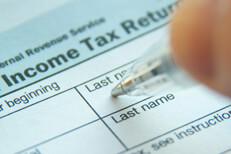 Photo of pen filling out 1040 form with focus on Income Tax Return text