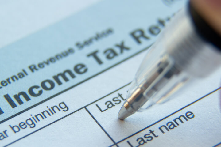 Close up photo of ball point pen in Last Name field of IRS form 1040