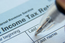 Close up photo of ball point pen in Last Name field of IRS form 1040