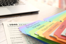 Desk with laptop for taxes Desktop with laptop, 1040 tax form, and rainbow-colored manila tax folders
