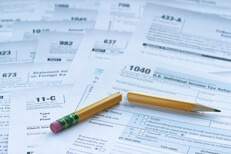 Many IRS tax forms laid out on desk with broken pencil concept for tax reform or simplification