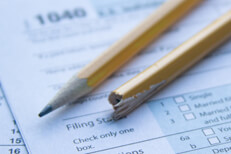 Broken, splintered pencil on IRS 1040 tax form showing tax filing frustration or confusion