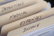 Manila filing folders with tax income, expenses, medical, and deductions and camera depth of field