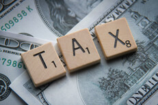 Tax Scrabble letters on money Tax Scrabble letters on scattered 100 dollar bills