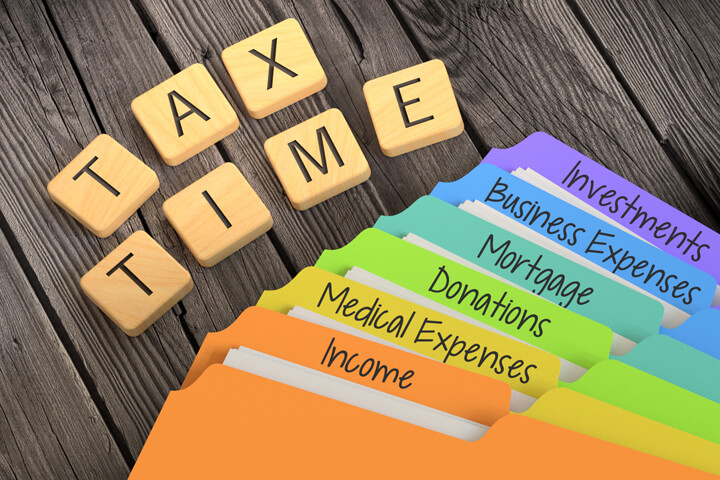 Fanned rainbow-colored manila folders for tax categories with Scrabble letters spelling TAX TIME