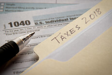 Manila folder with 2018 taxes tab on IRS form 1040 with ballpoint pen