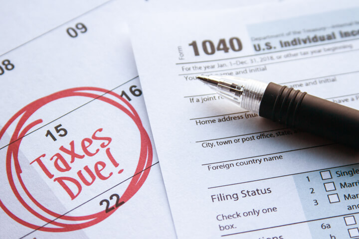 Calendar page with 15 circled and taxes due in red marker with 1040 form on top