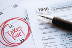 Calendar page with 15 circled and taxes due in red marker with 1040 form on top