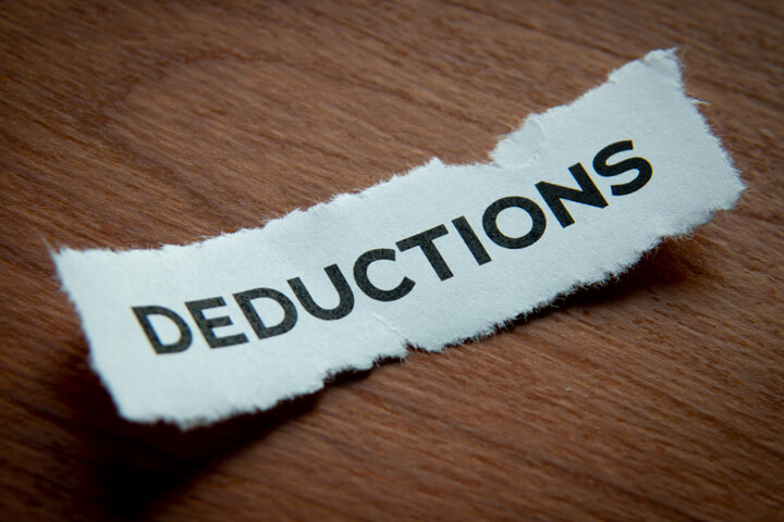 Torn piece of paper with Deductions text vignetted on woodgrain background