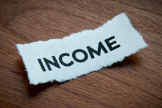 Torn piece of paper with word Income on depth of field and vignette on wood surface