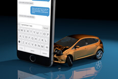 Orange car crashed into cell phone Orange compact car crashed into upright cell phone concept for texting while driving or distracted driving