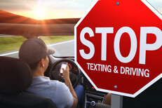 Man texting while driving Man driving into sunset texting on cell phone with stop texting and driving stop sign